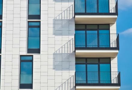 Contemporary urban apartment building with framed glass windows against clear blue sky.
