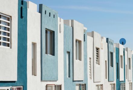 Geometric blue and white facade of a modern apartment building under a clear sky.