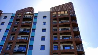 Explore the contemporary design and architecture of urban apartments with wooden accents and blue sky backdrop.